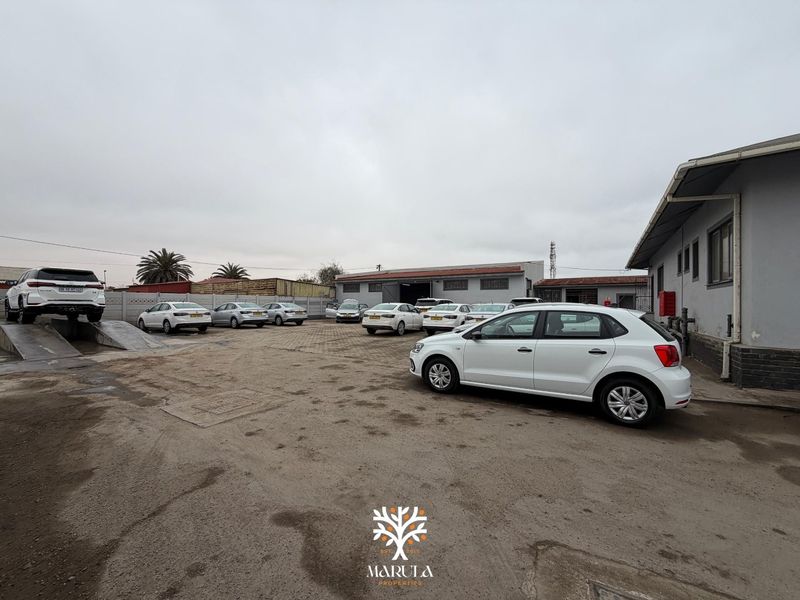 Spacious industrial yard area featuring paved surfaces, perimeter walling, and a vehicle ramp, suitable for commercial or automotive operations.