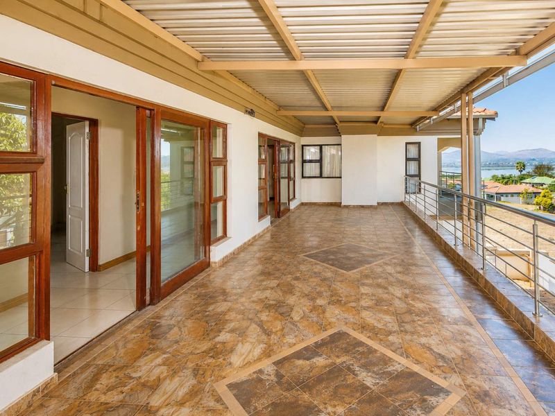 Spacious covered balcony featuring tiled flooring, timber-framed sliding doors, and stainless steel balustrades with scenic views.