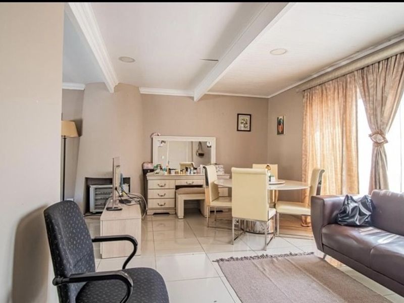 A spacious living area featuring tiled flooring, recessed ceiling lighting, and a built-in fireplace, offering a comfortable and functional layout.