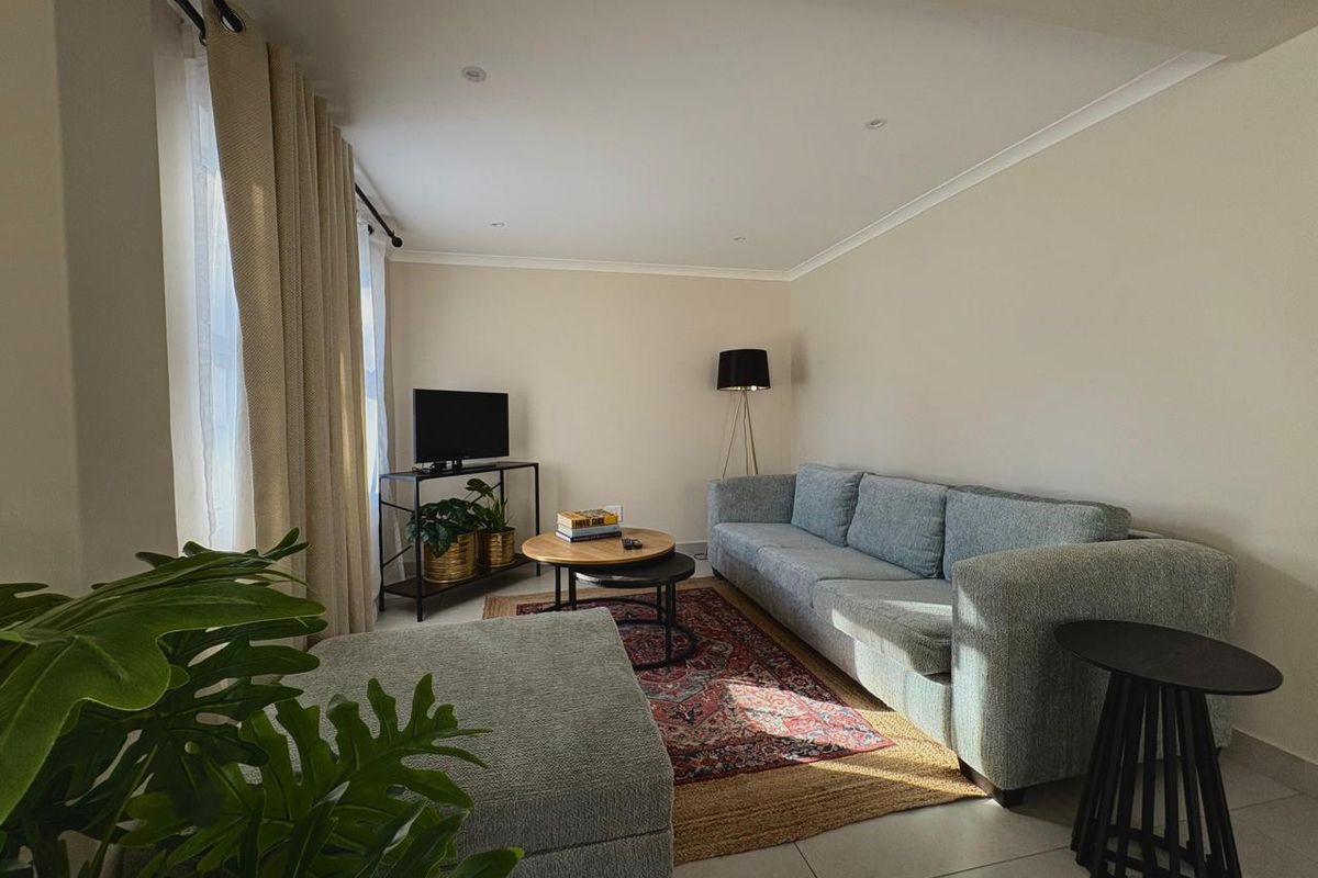A bright and well-maintained living room featuring neutral walls, tiled flooring, and recessed downlighting, creating a comfortable and inviting atmosphere.