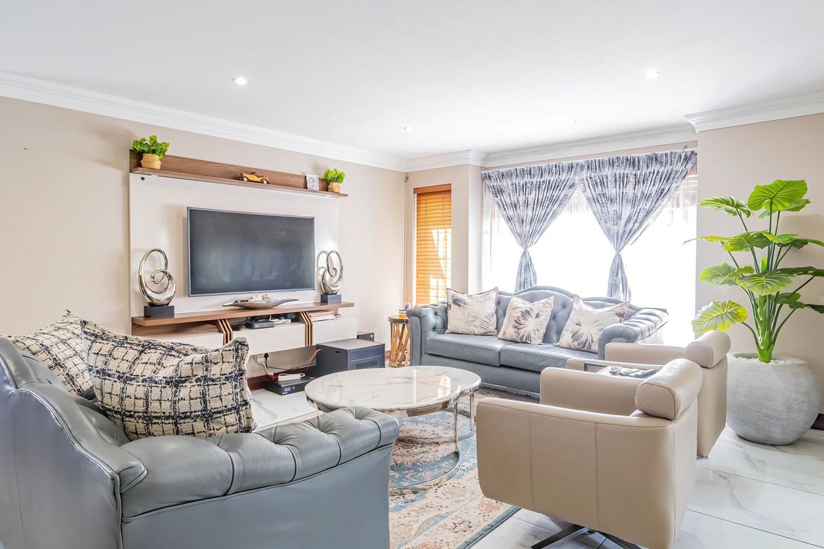 A bright and well-maintained living room featuring polished tiled flooring, crown molding, recessed lighting, and a custom built-in media unit.