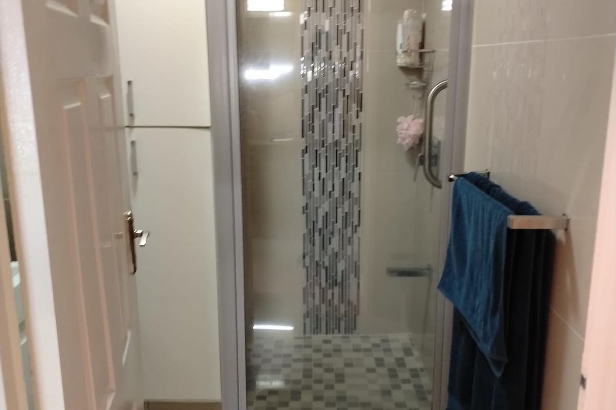 A modern bathroom featuring a glass-enclosed shower with decorative mosaic tile accents and built-in storage cabinetry.