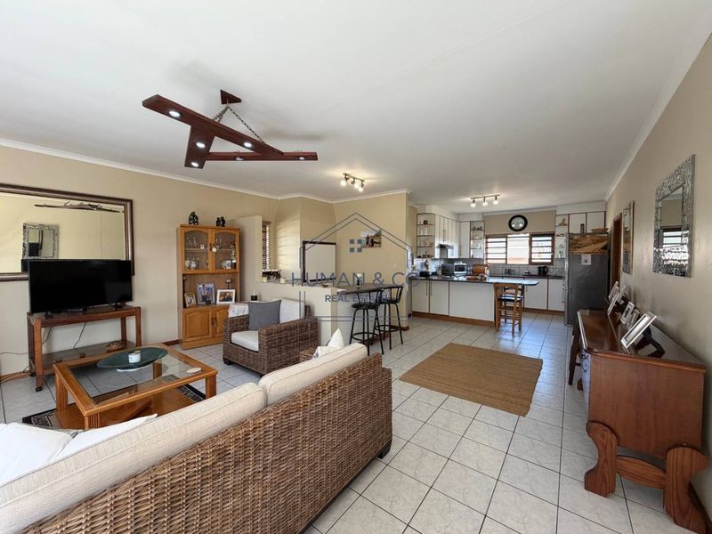Spacious open-plan living and kitchen area featuring tiled flooring, a functional breakfast bar, and ample cabinetry, offering a versatile layout for modern living.