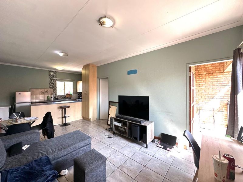 Open-plan living area featuring tiled flooring and a functional kitchen with built-in cabinetry, leading directly to an outdoor patio space.