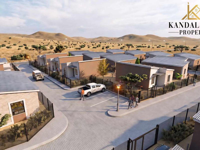 An aerial perspective of a modern townhouse development featuring paved driveways, secure metal fencing, and uniform architectural design within a landscaped estate.