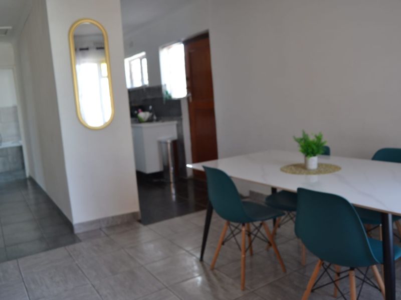 Open plan living and dining area featuring tiled flooring with a view into the adjacent kitchen space.
