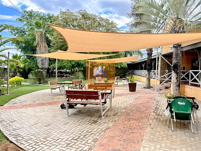 Outdoor patio area featuring paved flooring with brick accents and overhead shade sails, providing a functional space for guests.