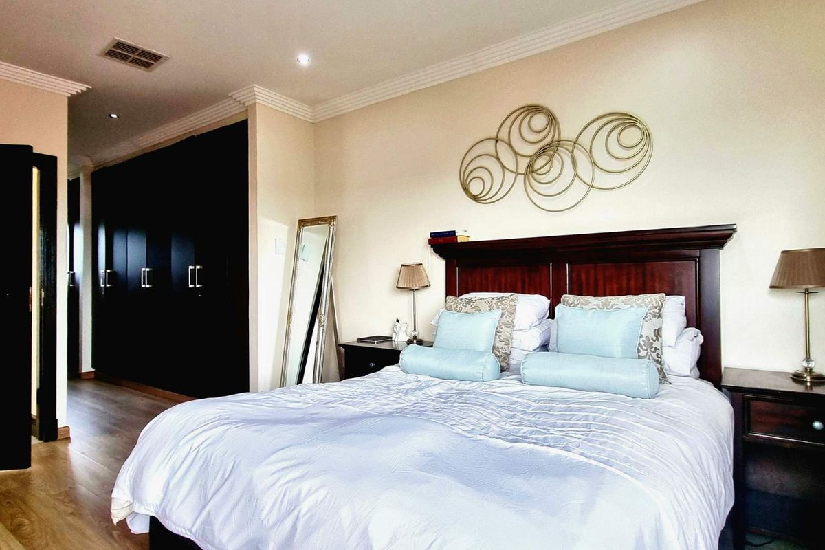 A well-maintained bedroom featuring dark built-in cupboards, laminate flooring, and decorative cornicing, providing a clean and functional living space.
