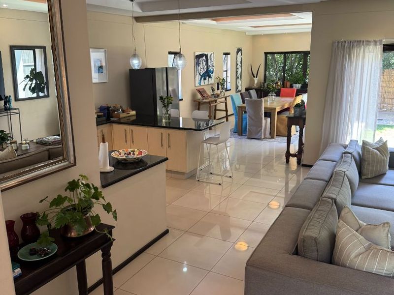 Spacious open-plan living area featuring a modern kitchen with granite countertops, tiled flooring, and recessed ceiling lighting, seamlessly flowing into the dining and lounge spaces.