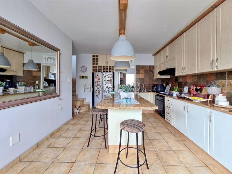 Spacious kitchen featuring granite countertops, a central island, ample built-in cabinetry, and tiled flooring, offering a functional layout for cooking and casual dining.