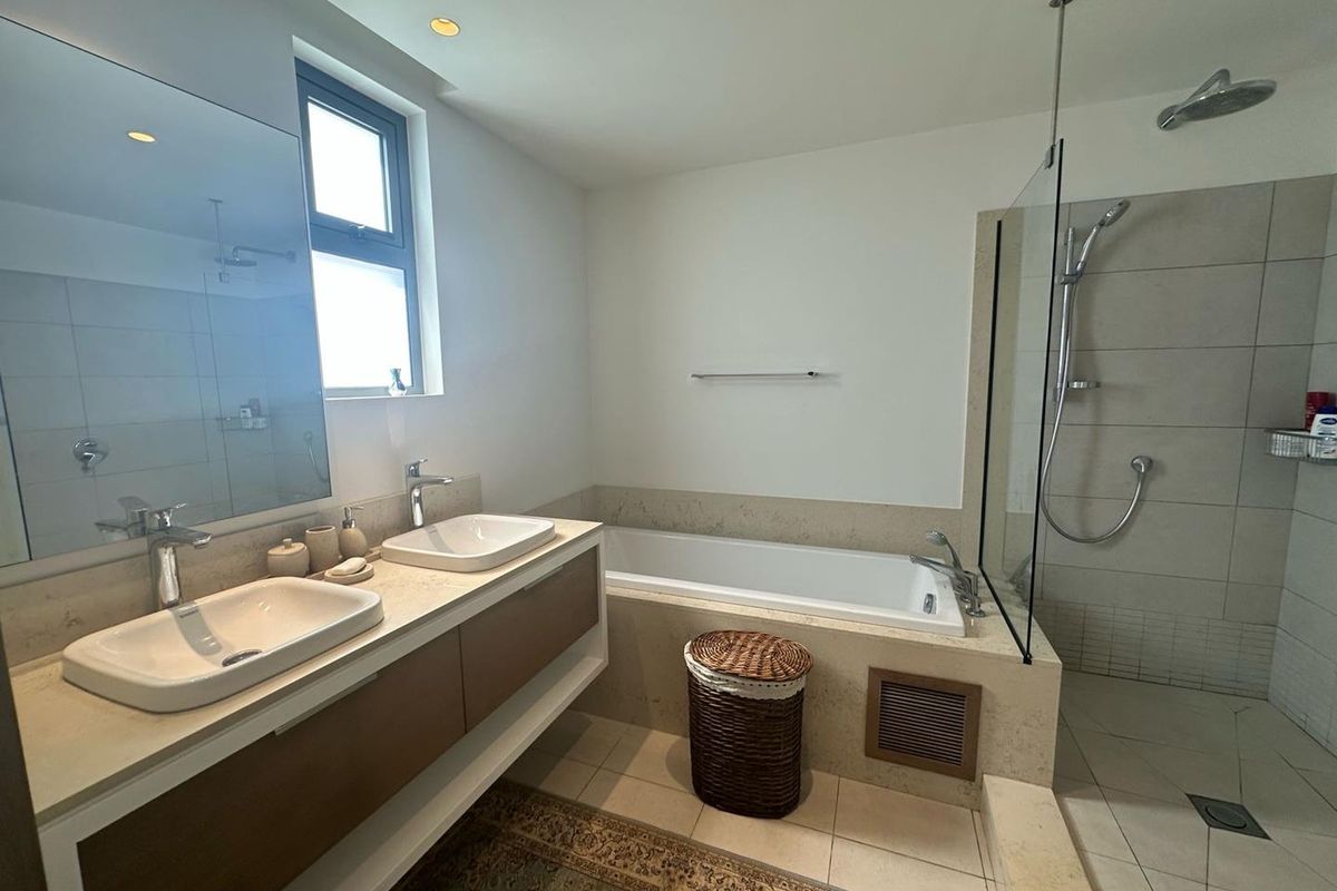 Modern bathroom featuring a double vanity with vessel sinks, a built-in bathtub, and a separate walk-in shower with a glass partition.