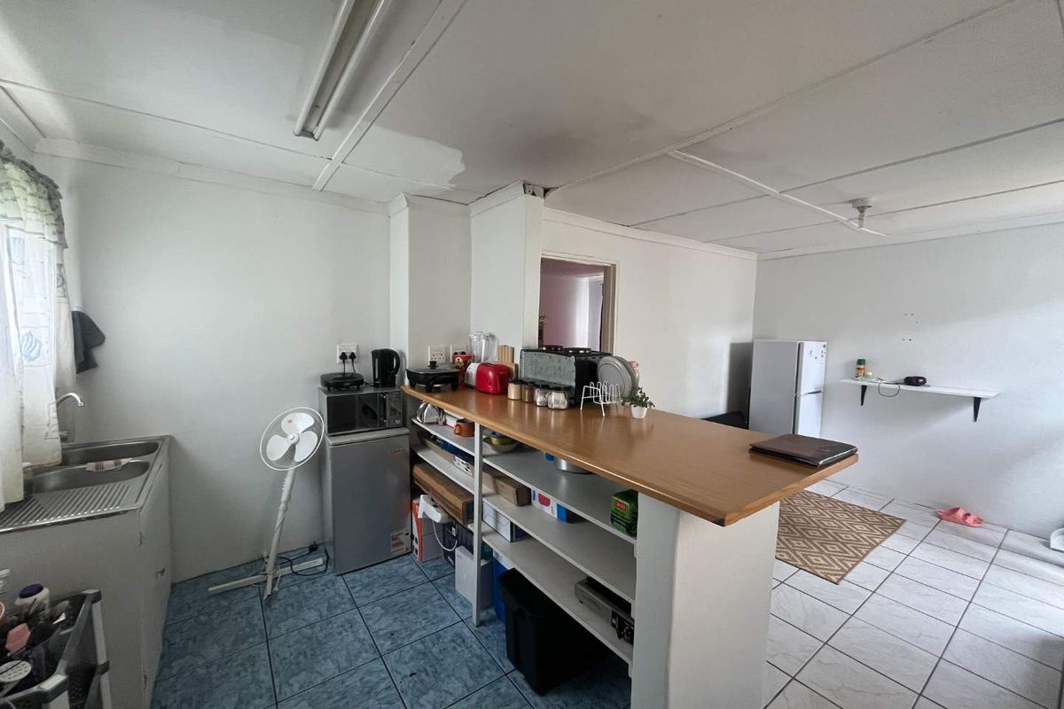 A functional kitchen area featuring a breakfast bar, tiled flooring, and basic cabinetry, offering potential for modernization and layout optimization.