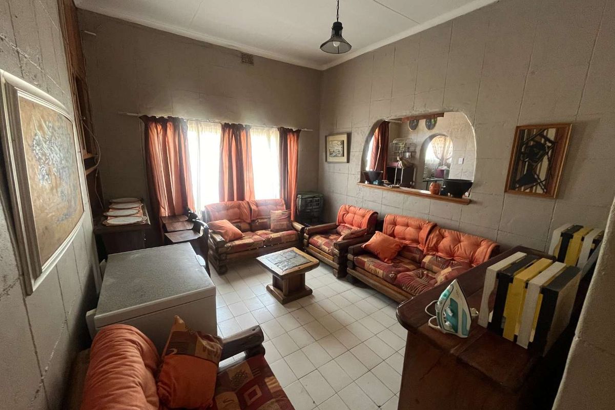 A living room featuring tiled flooring and a distinctive arched wall opening, providing a view into the adjacent space.