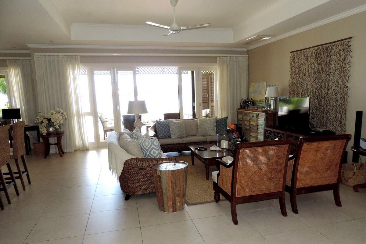 Spacious living area featuring large glass sliding doors leading to an outdoor patio, recessed ceiling with a central fan, and neutral tiled flooring.