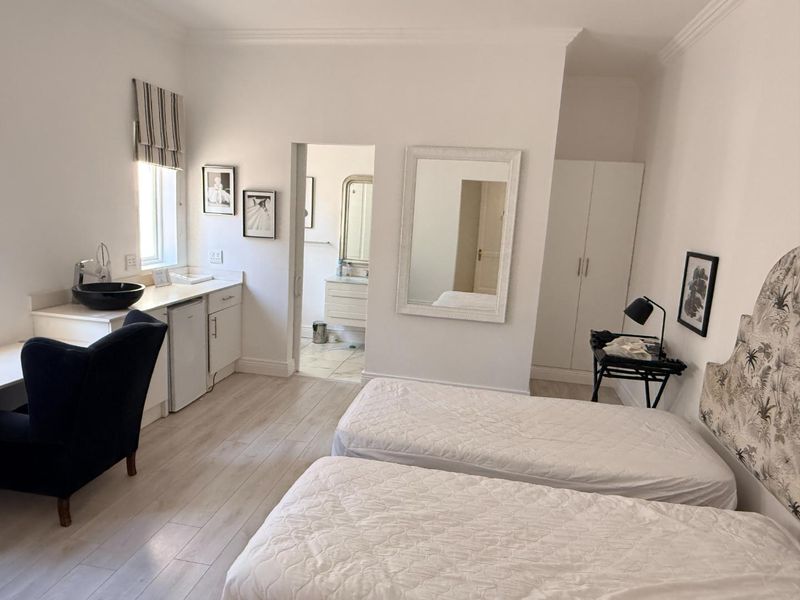 A well-maintained bedroom featuring built-in cabinetry with a basin, laminate flooring, and an en-suite bathroom access.
