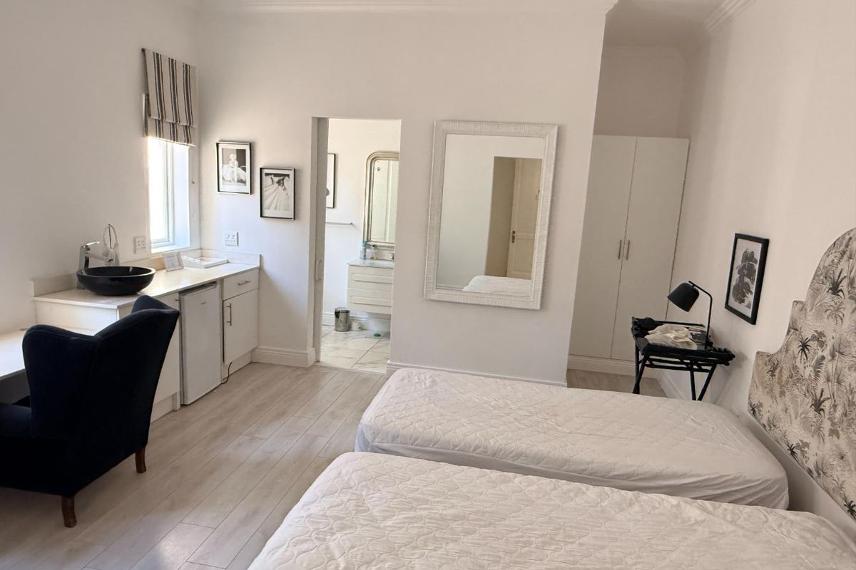 A well-maintained bedroom featuring built-in cabinetry with a basin, laminate flooring, and an en-suite bathroom access.
