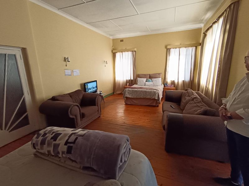 Spacious bedroom featuring original hardwood flooring and coved ceilings, offering a versatile layout with ample natural light from multiple windows.