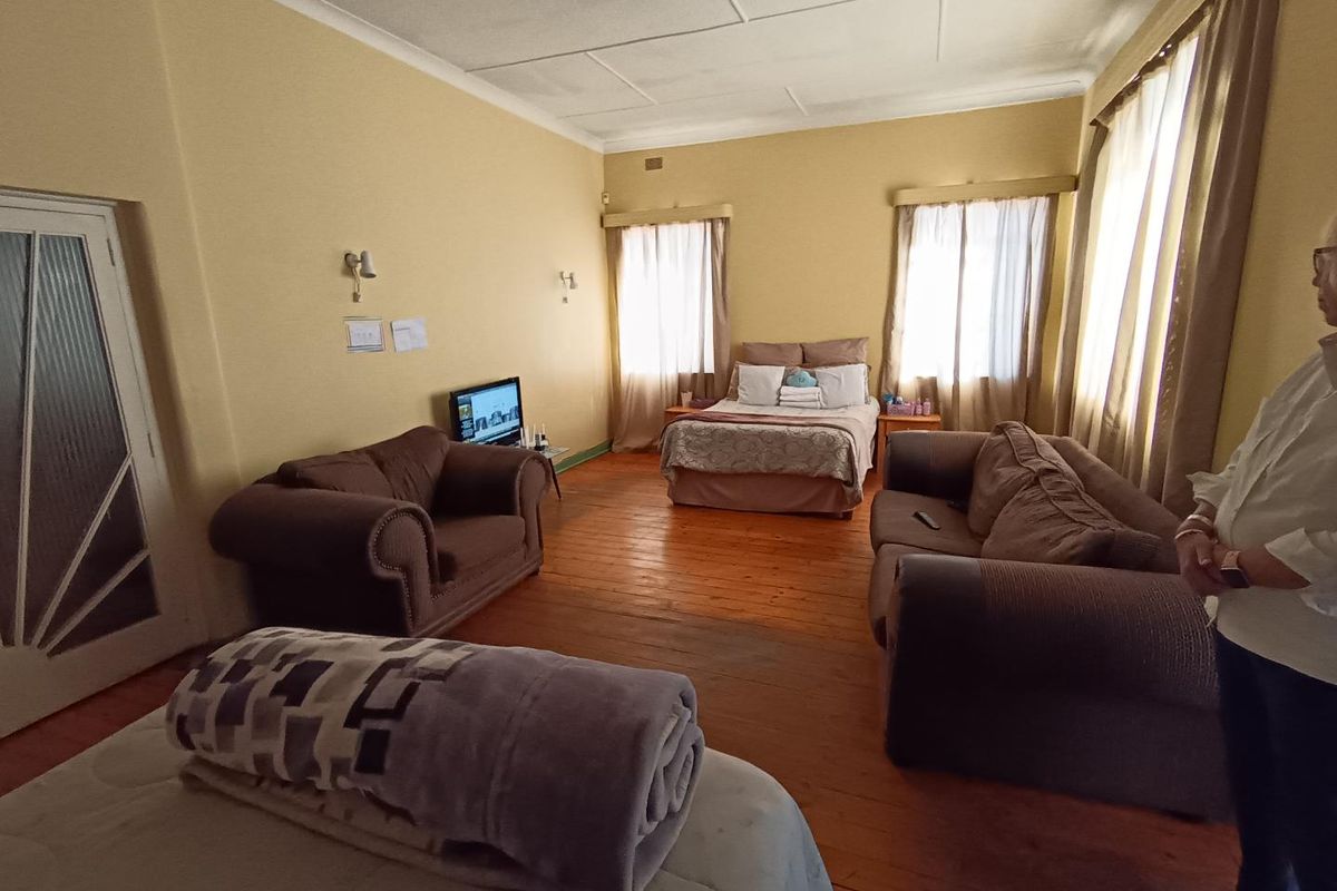Spacious bedroom featuring original hardwood flooring and coved ceilings, offering a versatile layout with ample natural light from multiple windows.