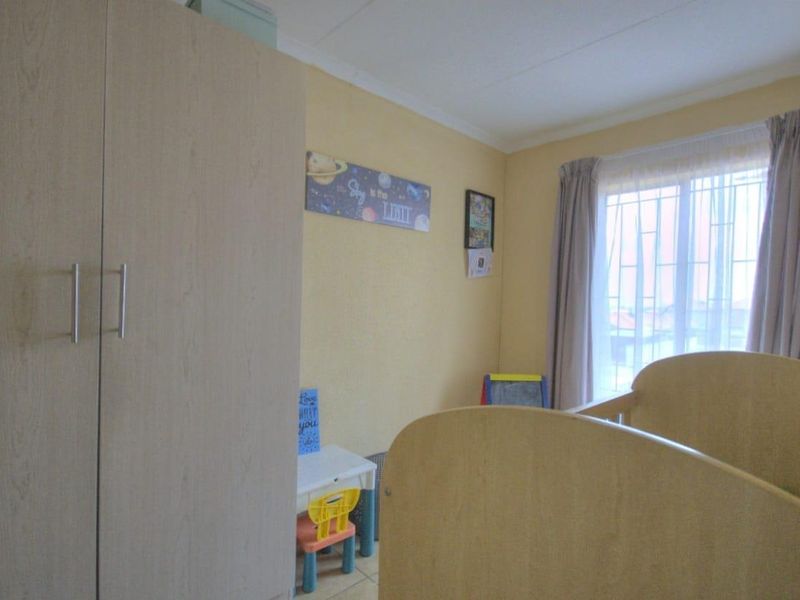 A bedroom featuring a built-in wardrobe and a window fitted with security bars, providing natural light and functional storage space.