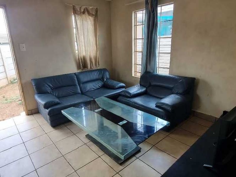 A living room featuring tiled flooring and direct access to the exterior, with visible wear on the wall surfaces.