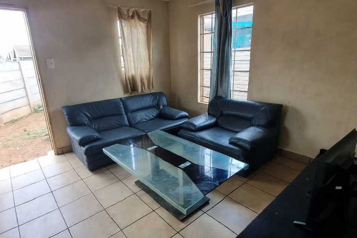 A living room featuring tiled flooring and direct access to the exterior, with visible wear on the wall surfaces.
