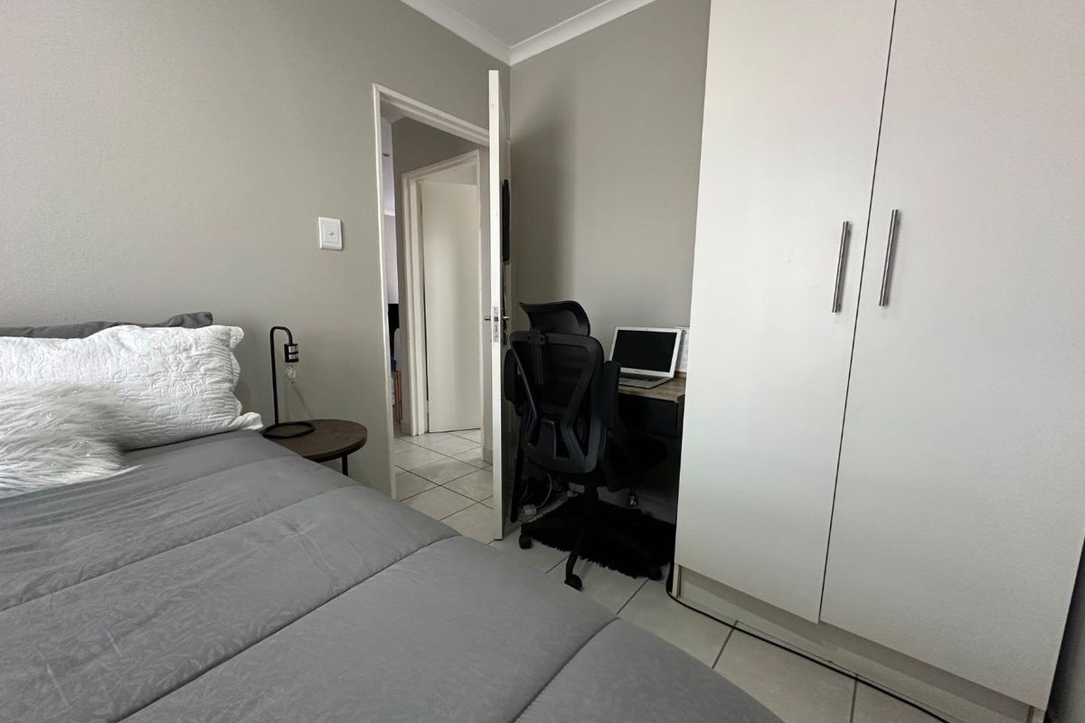 A bedroom featuring built-in white cabinetry, tiled flooring, and a doorway leading to a hallway.