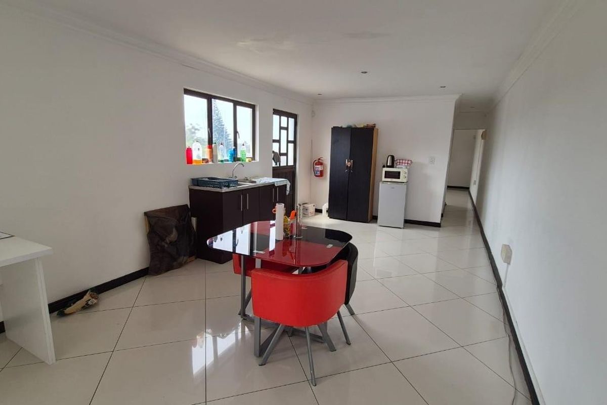 A functional kitchen area featuring tiled flooring, built-in cabinetry with a sink, and recessed lighting, offering a clean and practical layout.