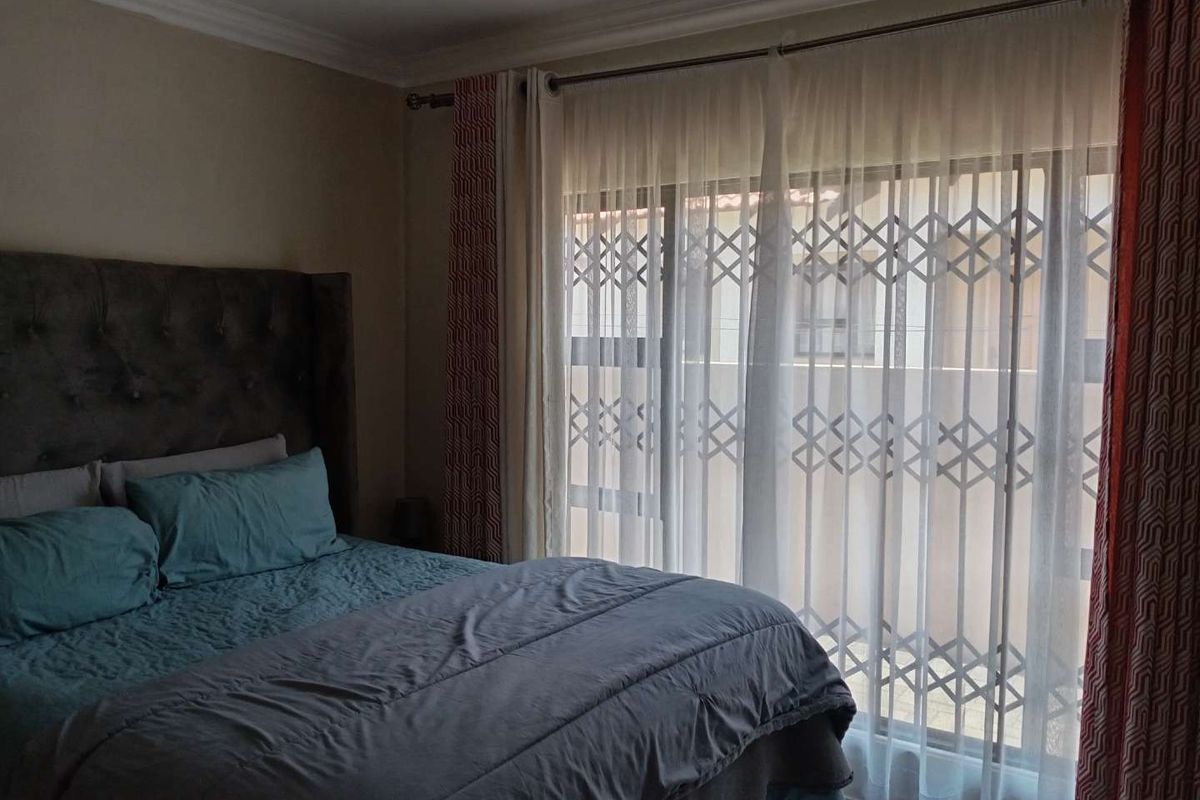 A bedroom featuring a large window with a security gate and neutral wall finishes.