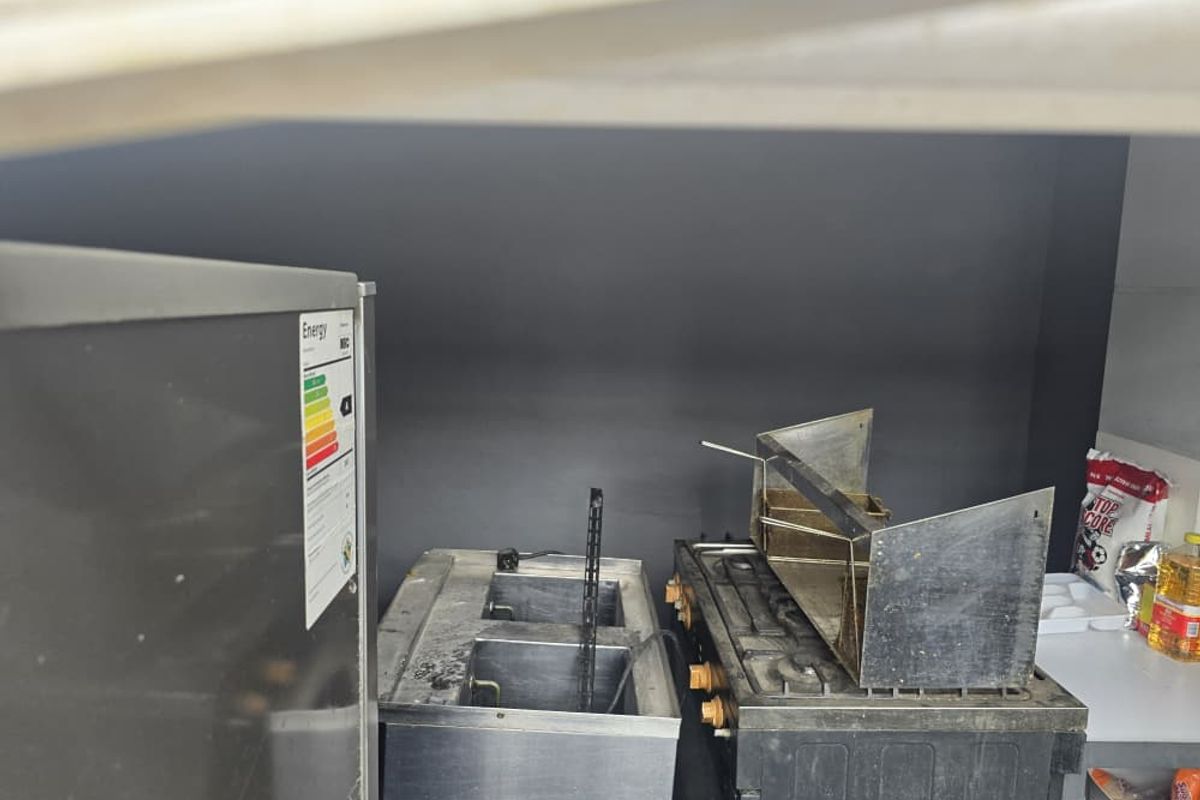 A commercial kitchen prep area featuring stainless steel deep fryers and cooking equipment in a compact workspace.
