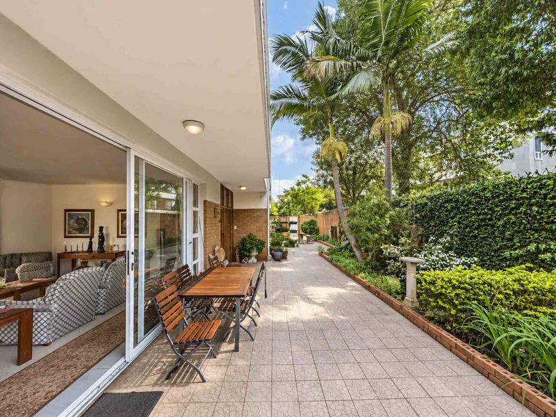A covered patio area featuring tiled flooring and large sliding glass doors that provide seamless access to the adjacent living space and garden.
