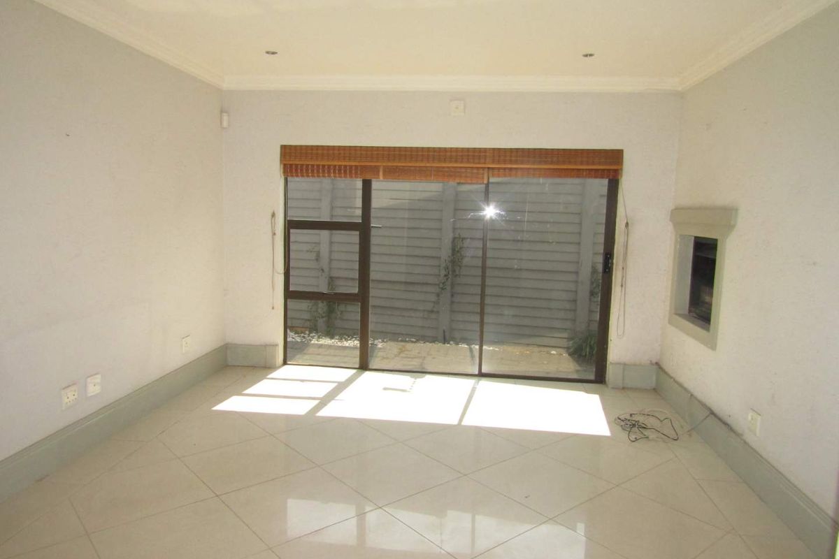 An empty living room featuring tiled flooring, recessed ceiling lighting, and a sliding glass door providing access to the rear exterior.