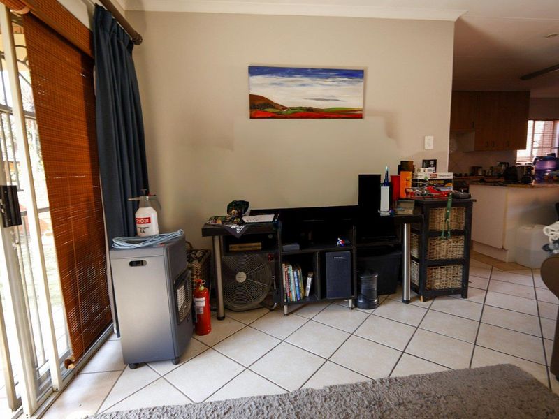 Open plan living area featuring ceramic floor tiles and a sliding glass door leading to the exterior, with a view into the kitchen area.