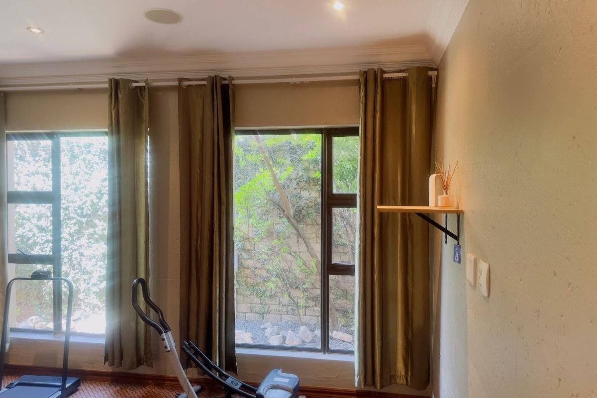 A bright room featuring large windows with garden views, recessed ceiling lighting, and patterned flooring, suitable for use as a bedroom or home office.