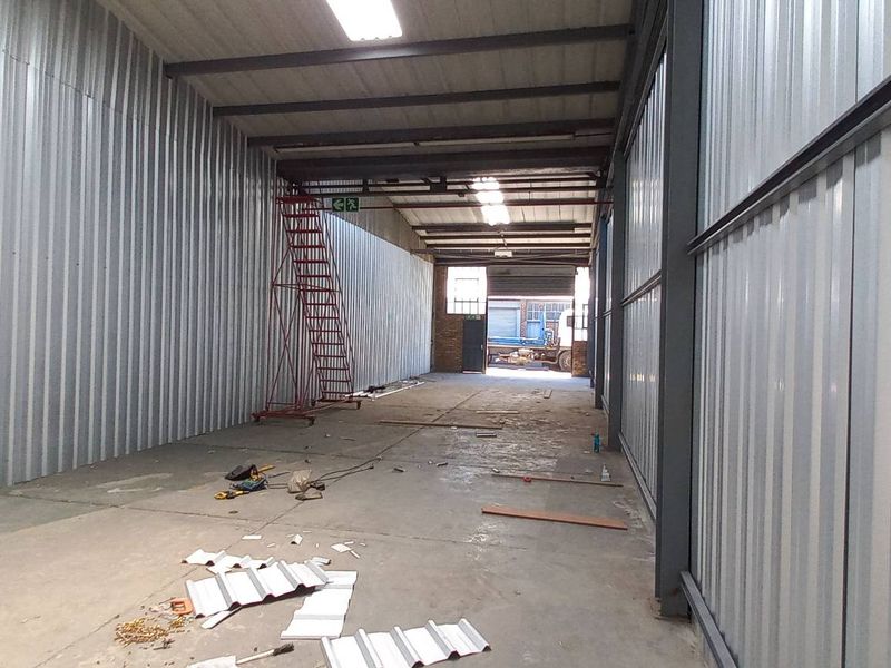 Spacious industrial utility area featuring corrugated metal walls, exposed steel roof trusses, and concrete flooring, suitable for storage or workshop use.