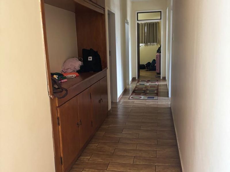 A functional hallway featuring wood-look tiled flooring and extensive built-in wooden storage cabinetry.