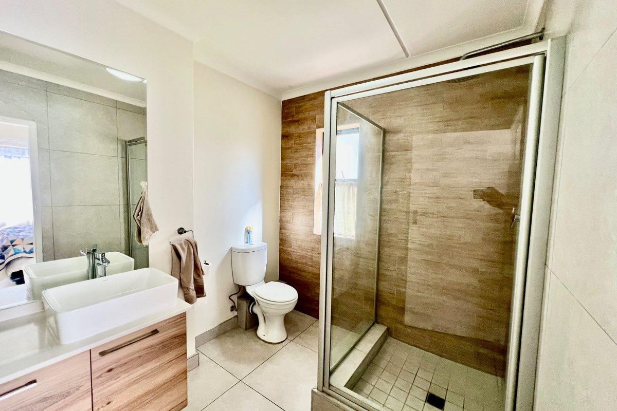Modern bathroom featuring a wood-finish vanity with a vessel sink, a glass-enclosed shower, and stylish wood-look feature wall tiling.