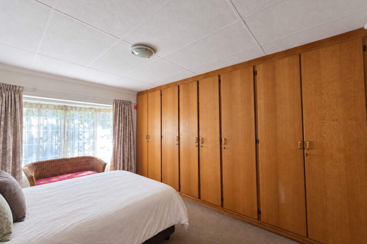 A bedroom featuring extensive floor-to-ceiling built-in wooden wardrobes, carpeted flooring, and a tiled ceiling.