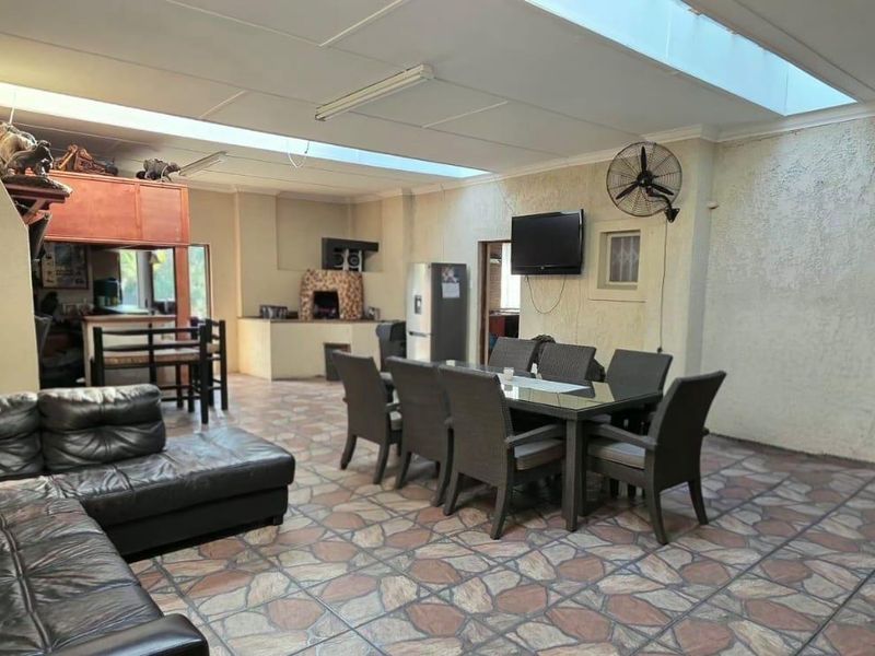 Spacious open-plan living and dining area featuring a built-in braai, large skylights for natural light, and durable tiled flooring.