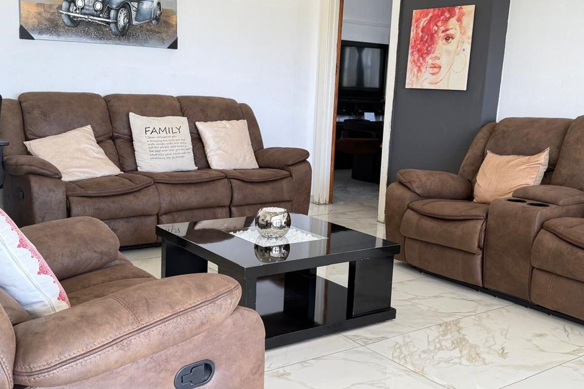 A living room featuring polished marble-look floor tiles and a neutral wall finish, providing a clean and functional space.
