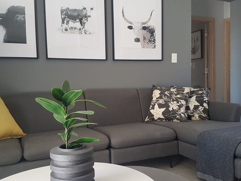 A well-maintained living room featuring neutral grey walls and tiled flooring, providing a clean and modern aesthetic.