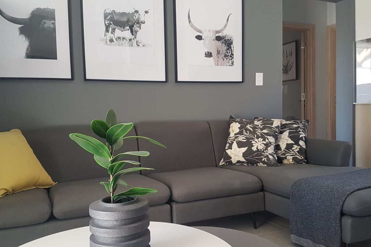 A well-maintained living room featuring neutral grey walls and tiled flooring, providing a clean and modern aesthetic.