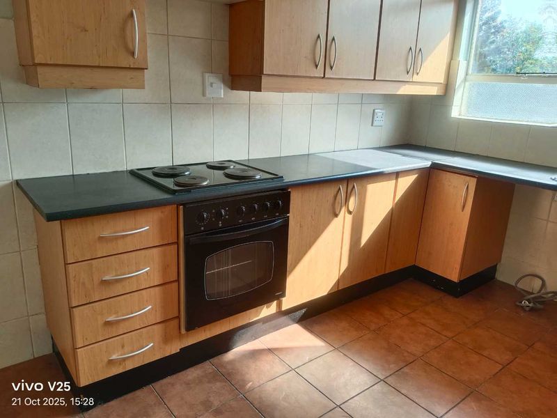 A functional kitchen featuring wooden cabinetry, a built-in oven and hob, tiled backsplash, and tiled flooring, offering a practical layout for daily use.
