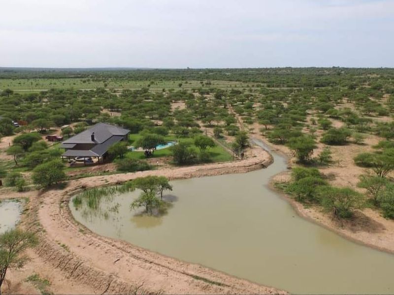 Aerial view of a game farm property featuring a main dwelling with a swimming pool, surrounded by natural bushveld and a private dam.
