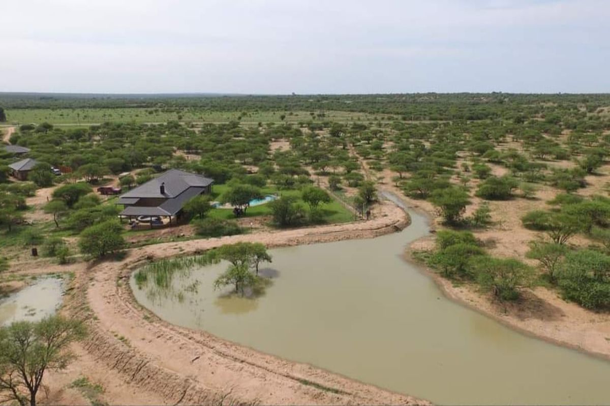 Aerial view of a game farm property featuring a main dwelling with a swimming pool, surrounded by natural bushveld and a private dam.