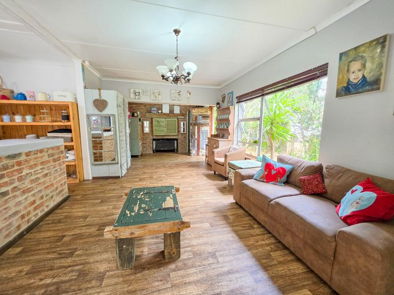 Spacious open-plan living area featuring exposed brick accents, wood-look flooring, and large windows that provide ample natural light.