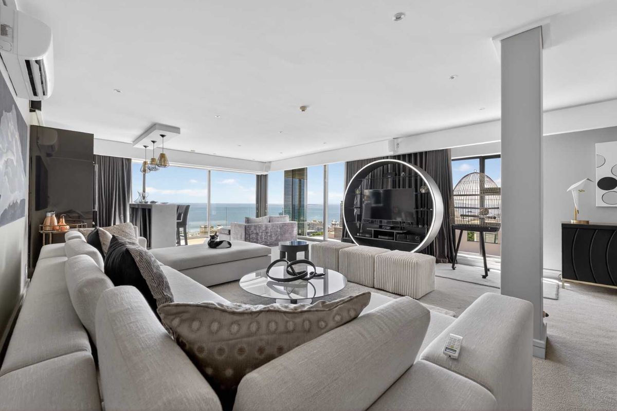 Spacious, modern living area featuring floor-to-ceiling windows with expansive ocean views, recessed lighting, and a sleek, open-plan layout.