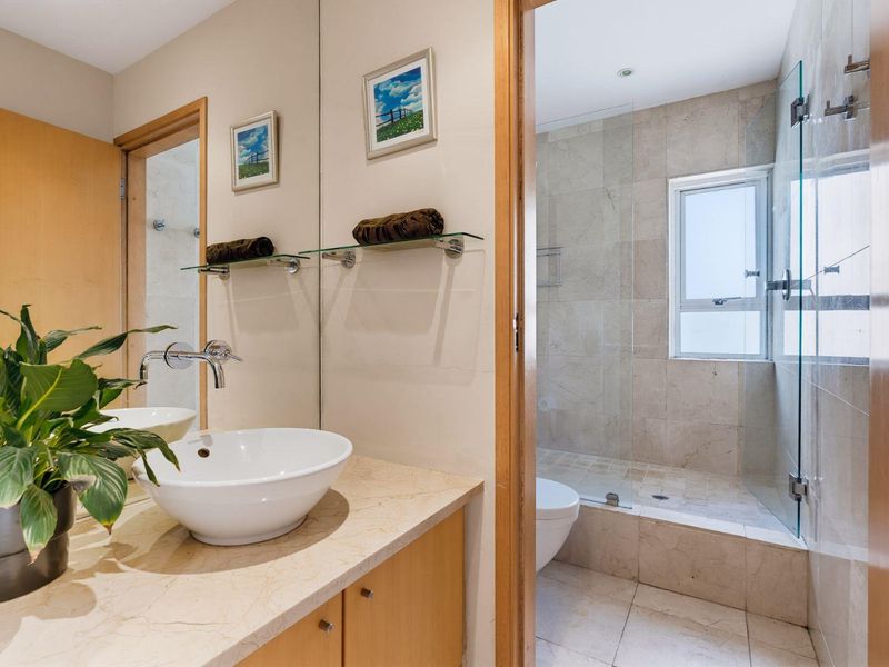 Modern bathroom featuring a stone vanity with a vessel sink, large mirror, and a separate walk-in shower with glass enclosure and stone tiling.