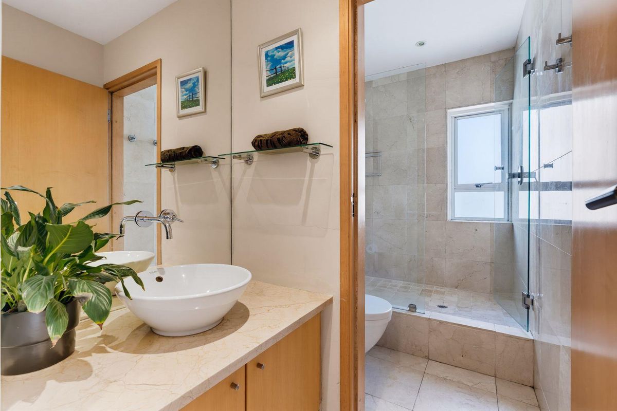 Modern bathroom featuring a stone vanity with a vessel sink, large mirror, and a separate walk-in shower with glass enclosure and stone tiling.