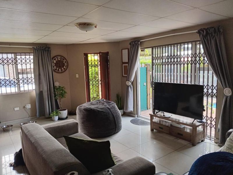 A living room featuring tiled flooring, security gates on windows and doors, and direct access to an outdoor area.