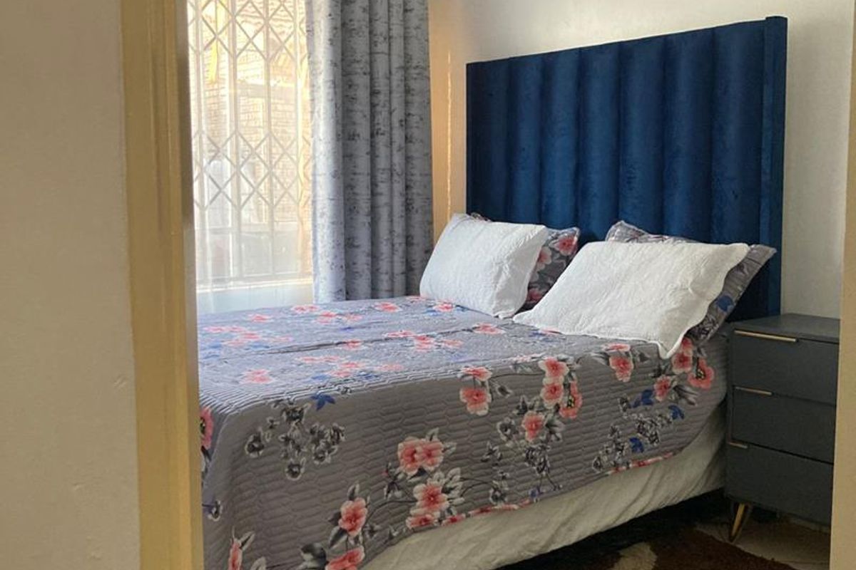 A bedroom featuring tiled flooring and a window with security bars, viewed from the doorway.